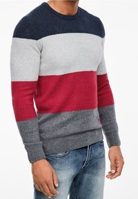 Pull en tricot avec un col rond, présentant des rayures bleu marine, gris, rouge et gris foncé. Fabriqué en matériau doux, avec des poignets et un ourlet côtelés.