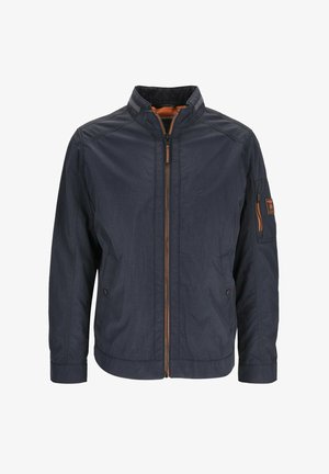 Navy blue zip-up jacket with stand collar, orange zipper details, chest pockets, and zippered pocket on left sleeve.