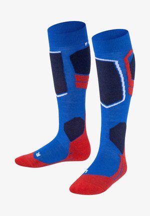 Chaussettes jusqu'aux genoux avec un corps bleu et des motifs géométriques rouges et navy, un tissu texturé, et des sections renforcées aux orteils et au talon en rouge.