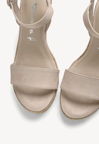Sandales ouvertes en daim beige avec brides à la cheville et semelles tressées style espadrille.