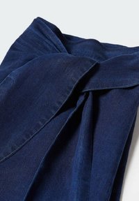 Marineblåt stof med en blød tekstur, der har en snoet knudedetalje. Materialet fremstår glat med en subtil glans uden synlige mønstre.