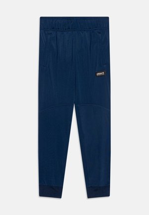 Granatowe spodnie dresowe Adidas Adventure z elastycznym pasem, bocznymi kieszeniami, ściągaczami przy kostkach i naszywką z logo na prawym udzie.