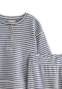 Zestaw loungewear w paski w jasnoszarym i granatowym kolorze, składający się z długiego rękawa bluzki z zapięciem na guziki oraz spodni z elastycznym paskiem w pasującym kolorze.