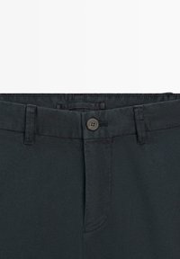 Donkergrijze tailleband van een broek met knoopsluiting, riemlussen en een verborgen ritssluiting.