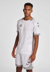 Hvid sportsuniform bestående af en kortærmet skjorte med grå detaljer og shorts, lavet af tekstureret stof med meshdesign og logo-detalje.