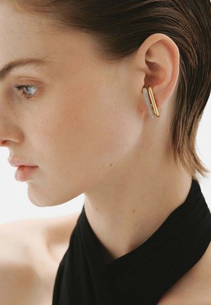 Pendientes de oro y plata con un diseño de doble capa, con una pieza exterior de oro lisa y una pieza interior de plata texturizada.