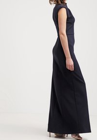 Marinblå maxiklänning med korta ärmar, slät tyg och rak silhuett som når anklarna. Stängd i ryggen med minimala detaljer.