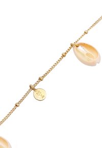 Guldkædearmbånd med en cowrie-musling og en lille rund charm med prægede detaljer, der fremhæver et delikat, tekstureret design.