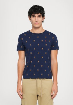 Tricou din bumbac bleumarin, cu guler rotund, având un model repetitiv în galben și roșu. Mâneci scurte și o croială normală.