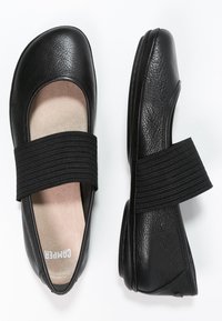 Zapatos planos de cuero negro con punta redonda y banda elástica en el empeine, con un acabado texturizado y planta color beige.
