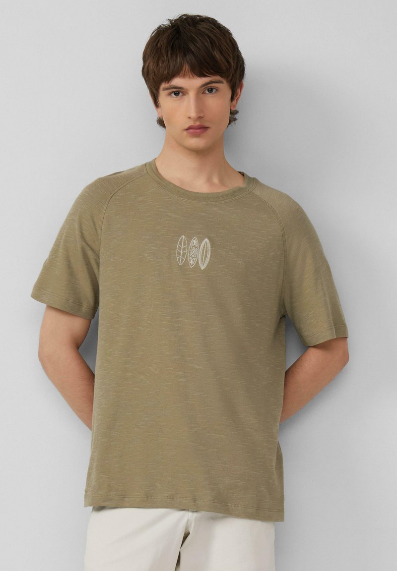 Oliwkowa koszulka z krótkim rękawem, teksturowany materiał, okrągły dekolt, z trzema białymi wzorami desek surfingowych na piersi.