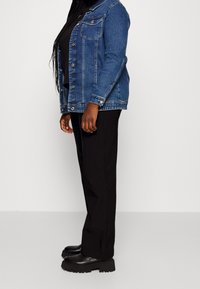 Jeansjacka i blått, med två bröstfickor, knäppningar och långa ärmar. Matchad med svarta byxor och svarta platåskor.