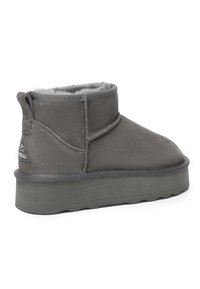 Graue Wildleder-Stiefeletten mit einem weichen Fellfutter, flacher Gummisohle, gesteppten Details und einer Zuglasche an der Ferse.