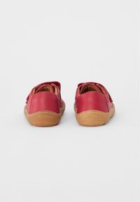 Red leather shoes with a textured finish, contrasting brown rubber soles, and a rounded design. Velcro strap closure at the back.
