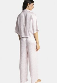 Ensemble de pyjama en satin rose clair comprenant un haut à col et à manches courtes et un pantalon à jambes larges avec un léger motif animal.