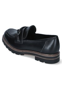 Mocassino in pelle nera con punta rialzata, cinturino decorativo e suola texture. Presenta una finitura liscia e una soletta centrale marrone a contrasto.
