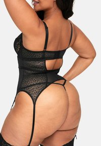 Czarny bodystocking z koronką, z regulowanymi ramiączkami, kwiatowym wzorem, otwartym tyłem i wysokimi bokami. Posiada delikatną teksturę siateczki.