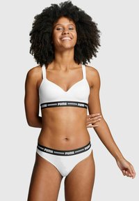 Weißes Unterwäsche-Set mit einem schlichten Bralette, verstellbaren Trägern und einem Bund, der ein schwarzes Logo zeigt; passende Bikinislip.