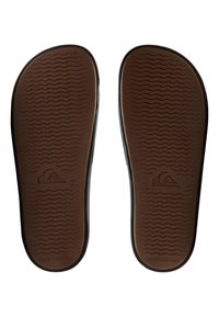 Hnedé gumené flip-flop podrážky s textúrovaným vlnitým vzorom a čiernym okrajom. Na jednej podrážke je vyrazené logo Quiksilver.