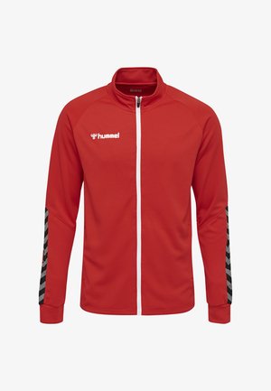 Rote Zip-Jacke aus strukturiertem Stoff. Merkmale sind ein weißer Reißverschluss, ein schwarz-graues Zickzackmuster an den Ärmeln und ein Logo auf der Brust.