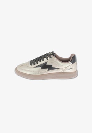 Beige sneaker with black lightning bolt design, black laces, and rubber sole, branded "Kaporal" near the heel.