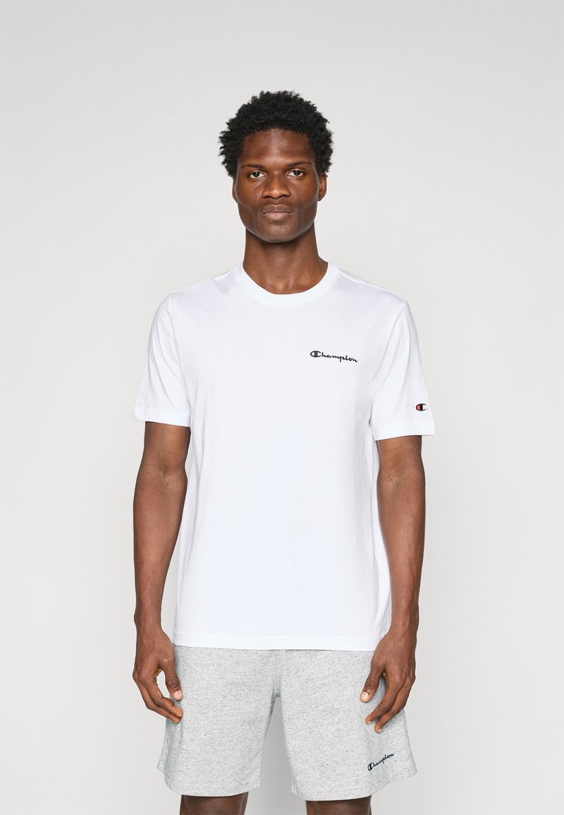 Hvid bomuld T-shirt med korte ærmer, der har et sort "Champion" logo på brystet og et lille logo på ærmet. Enkel design, rund hals.