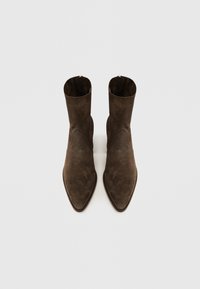 Botines de ante marrón con punta afilada y textura suave. Presentan un diseño sencillo y una cremallera trasera para el cierre.