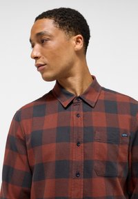 Rød og sort ternet flannel skjorte med knap-åndelej, lomme og mørke knapper. Teksturert stof med en blød finish.
