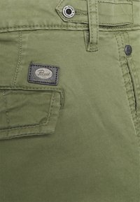 Olivgröna bomullscargoshorts med en framficka med logotyp, metallknappsstängning och synliga sömmdetaljer.