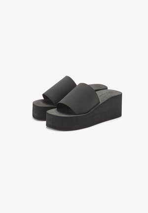 Schwarze Plateau-Sandalen mit doppelten Stoffriemen und einem strukturierten Fußbett. Die Sohle ist dick und geriffelt für Stabilität und Komfort.
