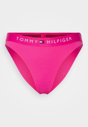 Funda de bikini rosa feita de tecido suave. Apresenta uma cintura elástica com marca "TOMMY HILFIGER" em branco, realçada com riscas preta e vermelha.
