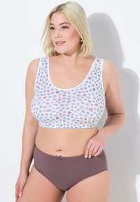 Vit kort topp med färggårdigt blommönster, parat med bruna högmidjade underkläder med en liten rosett som detalj. Slät textur.