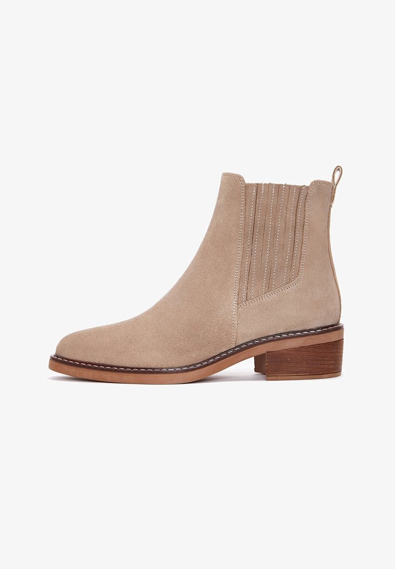 Stivale alla caviglia in suede beige con pannelli laterali elasticizzati, punta arrotondata, retro texturizzato e un tacco in legno basso e impilato.
