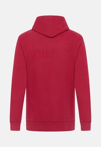 Piros kapucnis hoodie, kenguru zsebbel, húzózsinórral ellátott kapucnival és hímzett "SAND" részlettel a hátsó részen. Puha pamut keverék anyag.