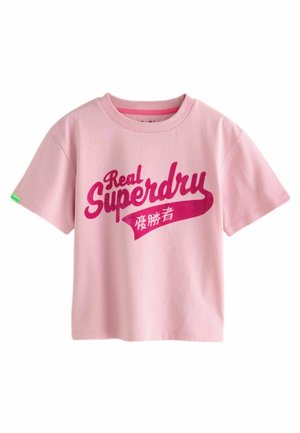 Růžové bavlněné tričko s krátkým rukávem, na kterém je výrazný červený nápis "Real Superdry" a malá zelená visačka na rukávu.