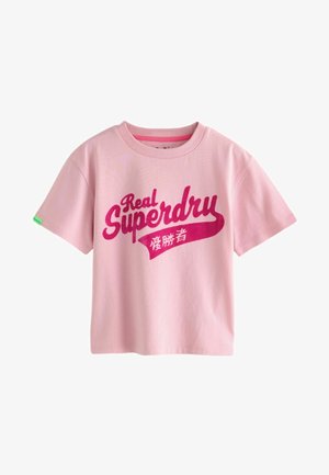 Vaaleanpunainen puuvillapaita lyhyillä hihoilla, jossa on rohkeaa punaista tekstiä "Real Superdry" ja pieni vihreä etiketti hihassa.