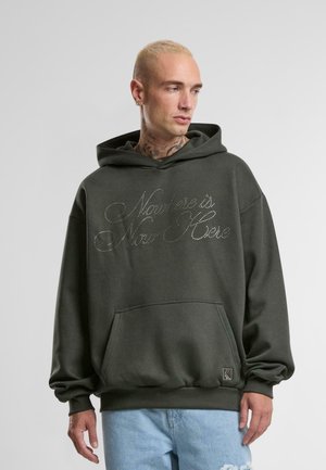 Dark green hoodie featuring a front pouch pocket, ribbed cuffs, and "Nothing is Now Here" in studded script across the chest.