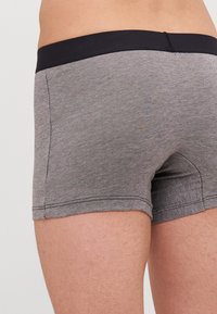Graue gewebte Boxershorts mit einem schwarzen dehnbaren Bund. Zu den Merkmalen gehören ein taillierter Schnitt und Seitennähte für eine enganliegende Passform.