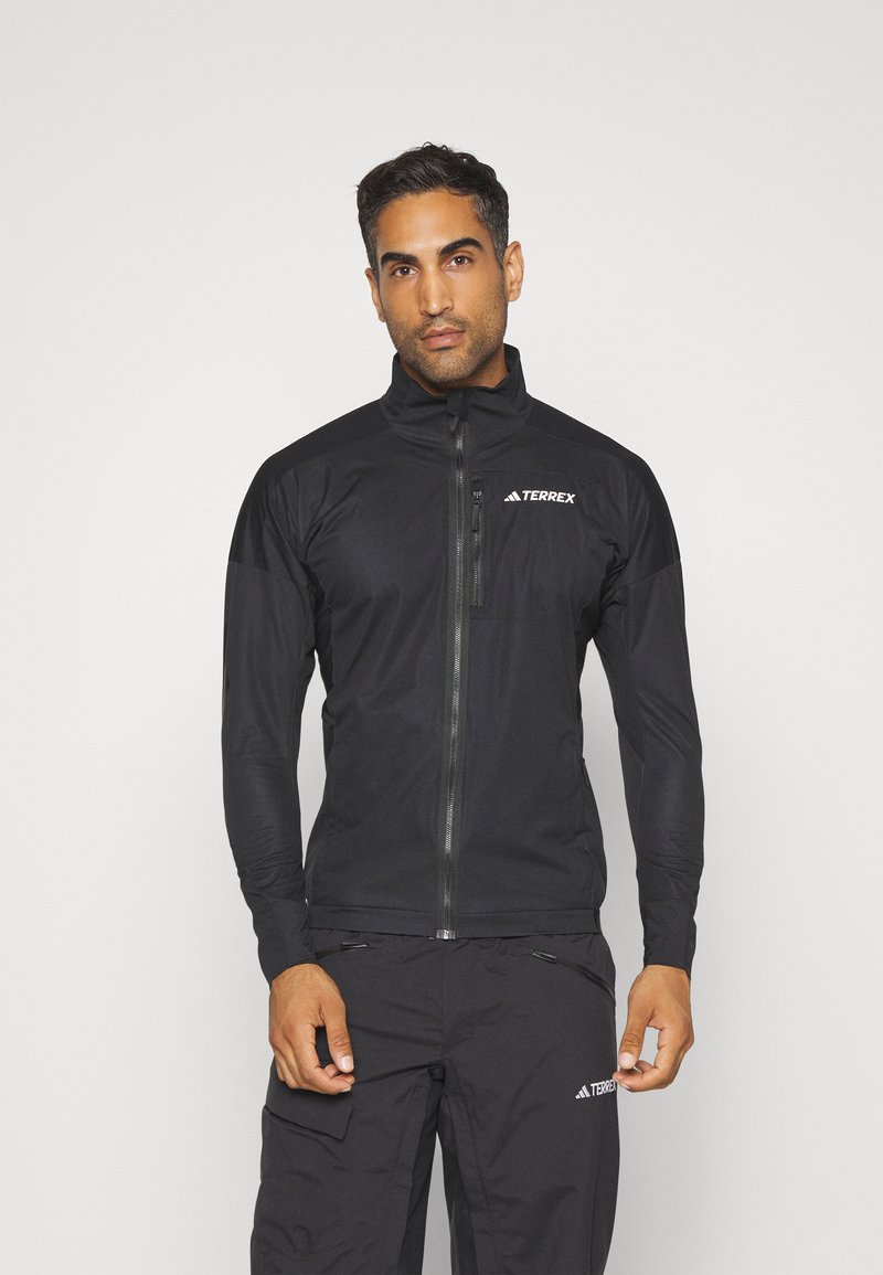 Black athletic jacket with a high collar, front zipper, and TERREX logo. Features long sleeves and a smooth, stretchy texture.
