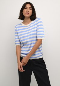 Stribet striktrøje i lys blå og creme, med korte ærmer og rund halsudskæring, parret med sorte bukser. Glat tekstur.