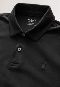 Sort slim fit poloshirt med krave og to knapper, med lille broderet hjertelogo på brystet, mærke Next, størrelse medium.