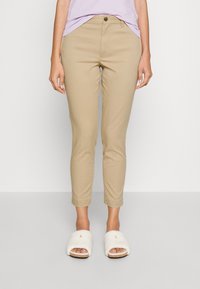 Khakifärgade chinos med slim fit, med knappstängning och ankellång nederkant. Mjuk tyg med en slät yta. Bärs med vita, fluffiga tofflor.