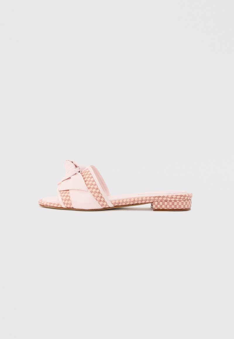 Ροζ επίπεδη σαγιονάρα με υφαντές λεπτομέρειες ιμάντα και κόμπο στο πάνω μέρος, εμφανίζεται σε απλό ανοιχτό φόντο.