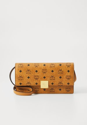 Sac bandoulière en cuir tan avec une texture matelassée, présentant une plaque logo en métal doré et des motifs MCM noirs en répétition.
