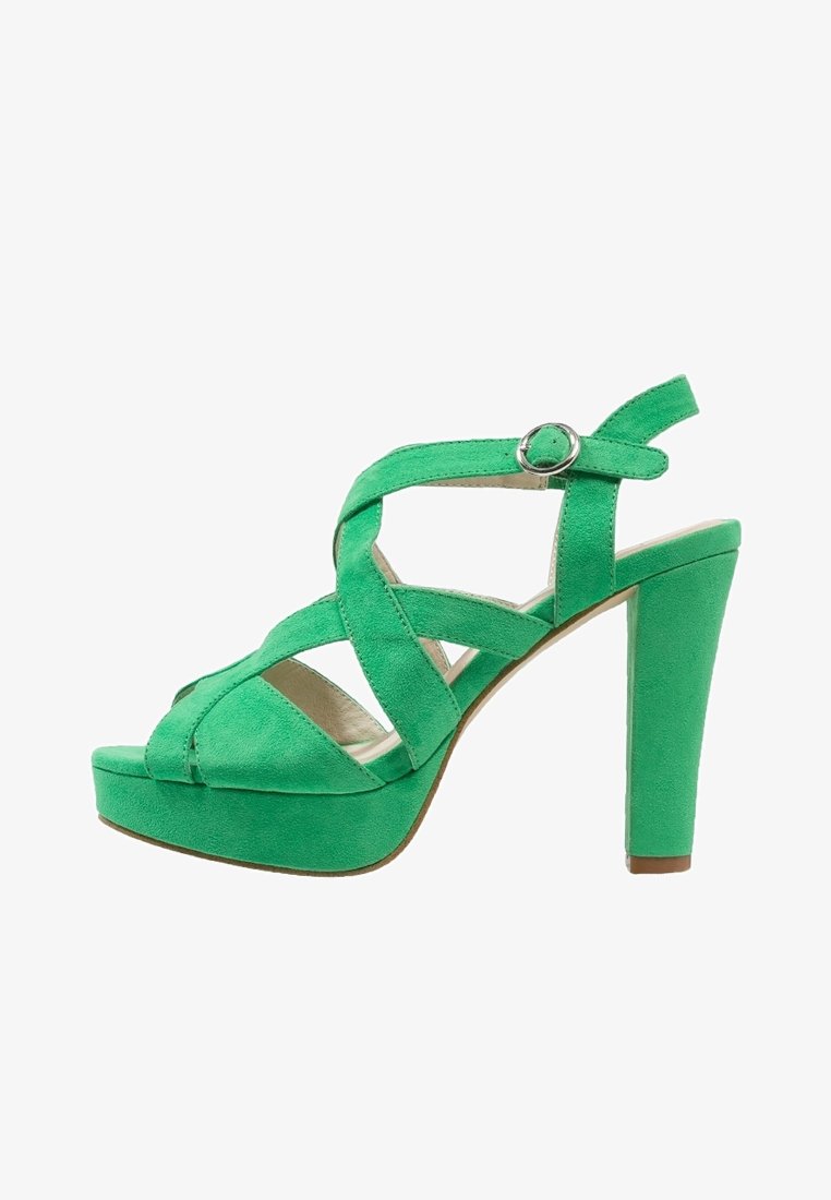 Zielone zamszowe sandały na wysokim obcasie z krzyżowym paskiem, akcentem w postaci klamry i platformą. Posiadają masywny obcas dla większej stabilności.