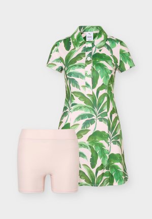 Lühikeste varrukatega kleit rohelise troopilise lehe mustriga ja esisõlmedega, kombineeritud ühtlase heledaroosa kitsaste pükstega.