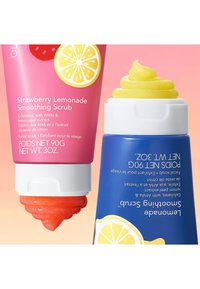 Due tube cosmetiche affiancate: una tubetto rosa con grafiche di fragole e limoni e un tubetto blu con un tappo giallo a spirale, entrambe contenenti scrub esfolianti.