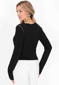 Top negru cu mâneci lungi, cu decolteu ondulat, design ajustat și accente decorative cu mărgele pe umeri, realizat dintr-un material neted și elastic.