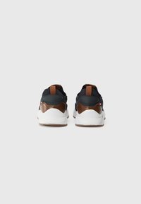 Black mesh and leather sneakers with brown accents, white soles, and a brown tab at the heel. Design features a sleek and modern shape.
