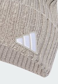 Light grey knit beanie featuring vertical ribbed texture and a white fabric logo patch with three angled stripes.